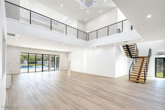 unfurnished living room featuring a towering ceiling and light hardwood / wood-style flooring