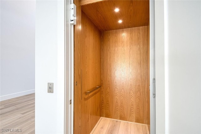 interior details featuring hardwood / wood-style floors, elevator, and wood ceiling