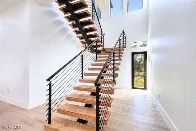 stairway featuring a towering ceiling and hardwood / wood-style floors