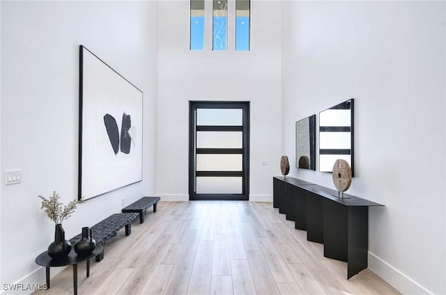 foyer with a high ceiling, baseboards, and light wood-type flooring