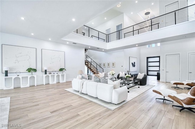 living area with stairs, recessed lighting, wood finished floors, and a towering ceiling