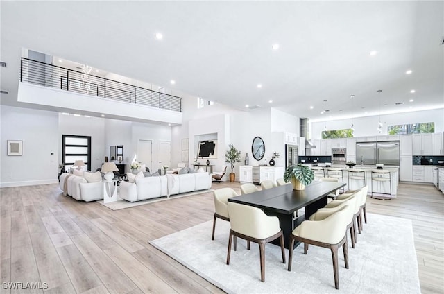 dining space featuring recessed lighting, a high ceiling, and light wood-style floors