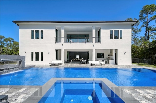 back of property featuring fence, an in ground hot tub, a balcony, an outdoor pool, and a patio