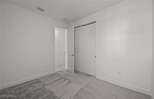 unfurnished bedroom featuring light colored carpet and a closet