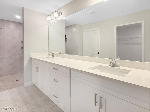 bathroom featuring vanity, tile patterned flooring, and tiled shower