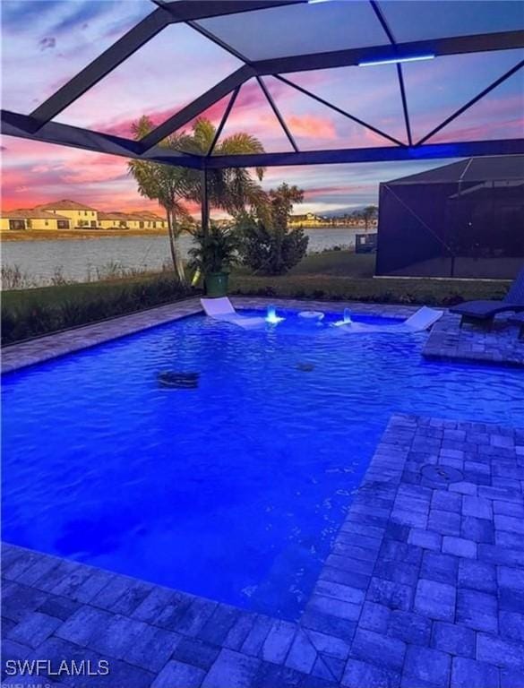 pool at dusk featuring pool water feature and glass enclosure