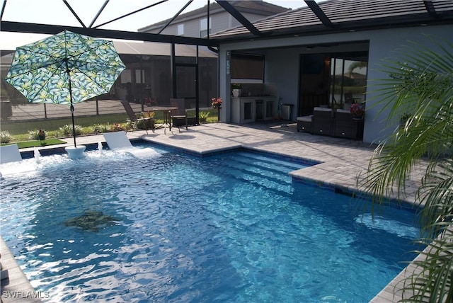 view of pool with glass enclosure, exterior kitchen, and a patio