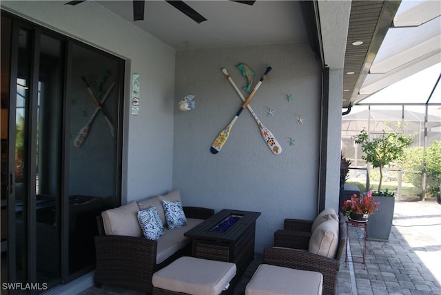 view of patio / terrace featuring ceiling fan, an outdoor living space with a fire pit, and glass enclosure