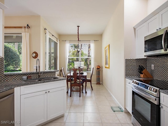 kitchen with sink, white cabinetry, stainless steel appliances, decorative backsplash, and decorative light fixtures