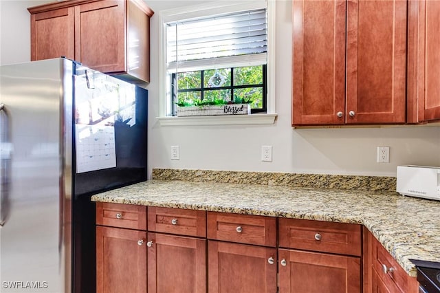 kitchen featuring light stone counters and stainless steel fridge