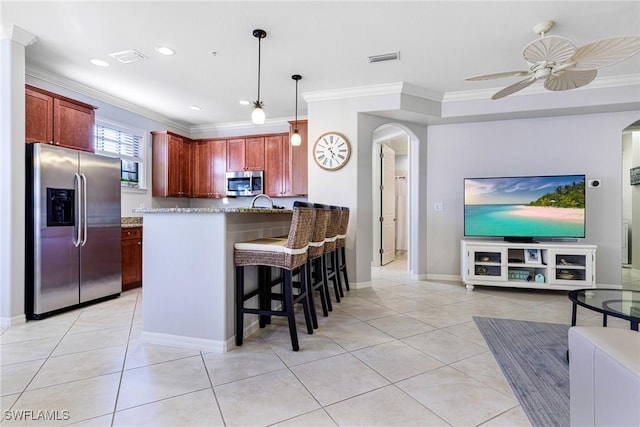 kitchen featuring light tile patterned floors, decorative light fixtures, a kitchen breakfast bar, and appliances with stainless steel finishes