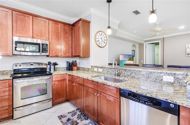 kitchen featuring sink, hanging light fixtures, ornamental molding, stainless steel appliances, and light stone countertops