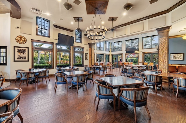 dining area featuring a high ceiling, decorative columns, and dark hardwood / wood-style flooring