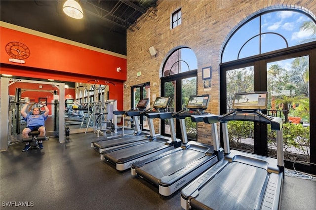 gym featuring a high ceiling, plenty of natural light, and french doors