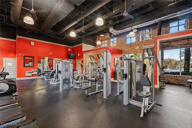 exercise room with a high ceiling and brick wall