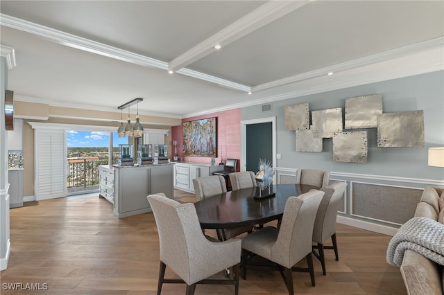 dining area featuring an inviting chandelier, ornamental molding, beam ceiling, and light wood-type flooring