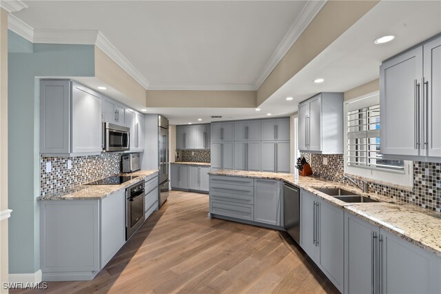 kitchen featuring stainless steel appliances, gray cabinets, sink, and light stone counters