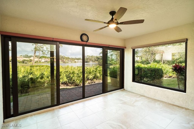 unfurnished sunroom featuring a water view and ceiling fan