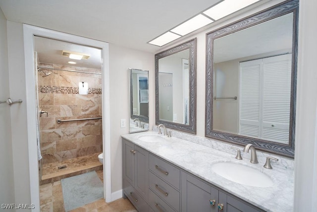 bathroom with a tile shower, vanity, and toilet