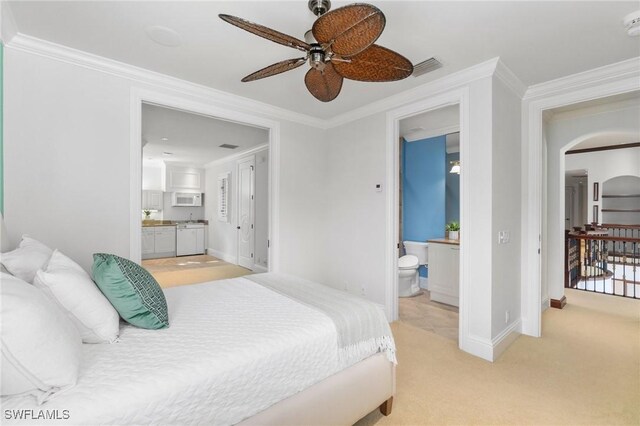 bedroom featuring ensuite bath, arched walkways, ornamental molding, and light colored carpet