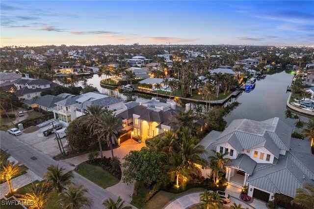 aerial view at dusk with a water view and a residential view