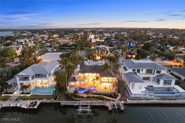 aerial view at dusk featuring a water view and a residential view