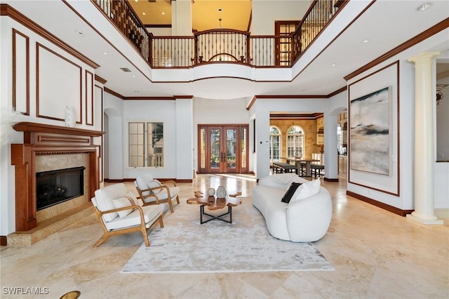 living area with crown molding, decorative columns, baseboards, and a premium fireplace