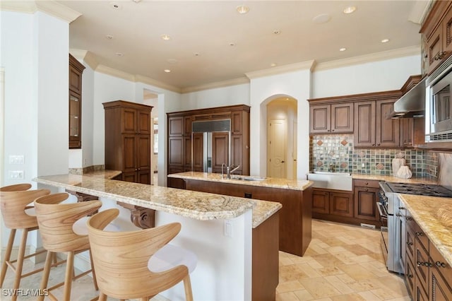 kitchen featuring high quality appliances, a center island, a peninsula, a kitchen bar, and backsplash