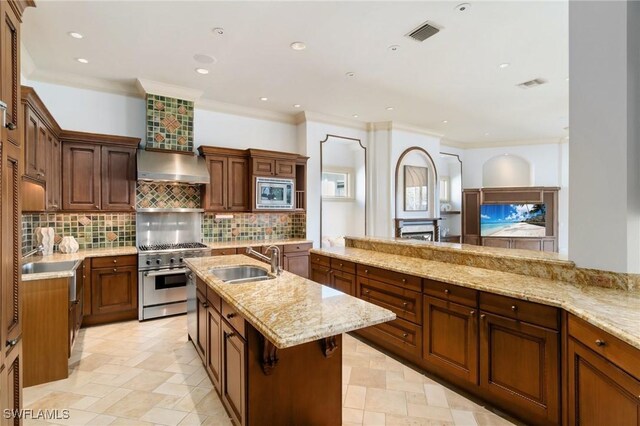 kitchen with stainless steel appliances, wall chimney range hood, a sink, and visible vents