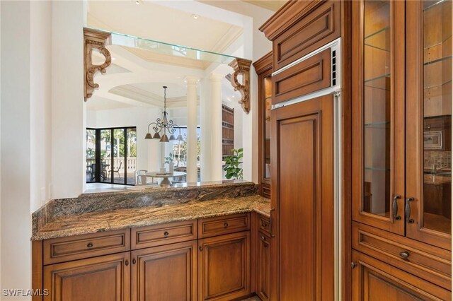 bar with hanging light fixtures, decorative columns, ornamental molding, and a chandelier