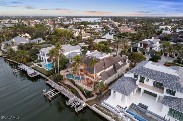 aerial view at dusk featuring a residential view and a water view