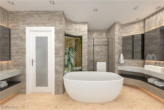 full bath featuring a freestanding tub, recessed lighting, a sink, tile walls, and a stall shower