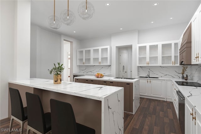 kitchen featuring dark wood finished floors, a kitchen island, glass insert cabinets, black electric stovetop, and a sink