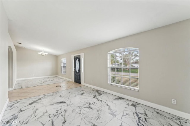 unfurnished room with a notable chandelier