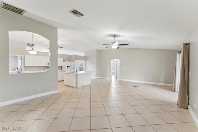 unfurnished living room with light tile patterned flooring, ceiling fan, lofted ceiling, and sink