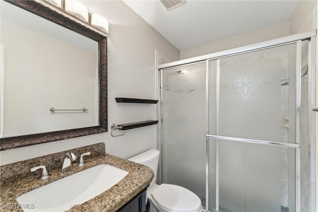 bathroom featuring vanity, a shower with door, and toilet