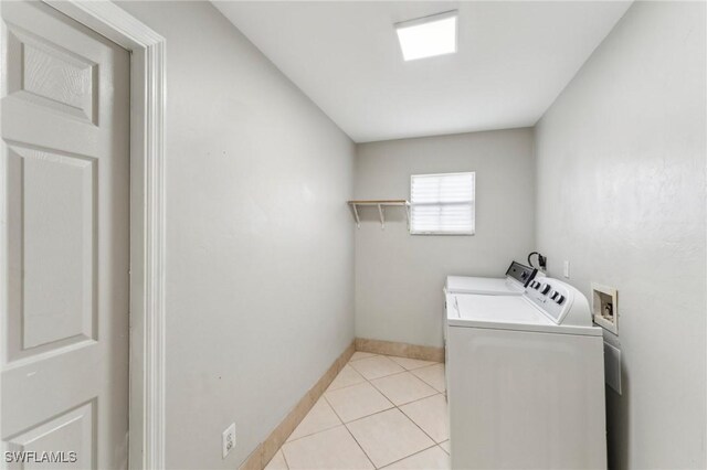 clothes washing area with light tile patterned floors and washer and clothes dryer