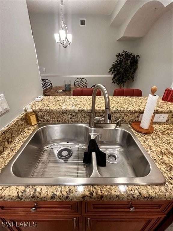 interior details with visible vents, pendant lighting, a sink, and a chandelier