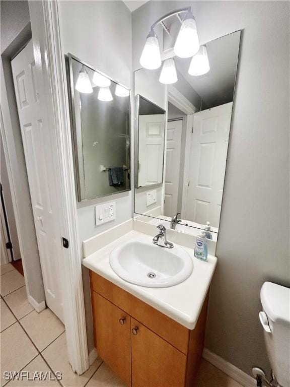 bathroom with tile patterned flooring, toilet, vanity, and baseboards