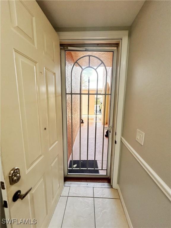 doorway to outside with light tile patterned floors and baseboards