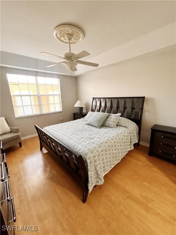 bedroom with a ceiling fan, baseboards, and wood finished floors