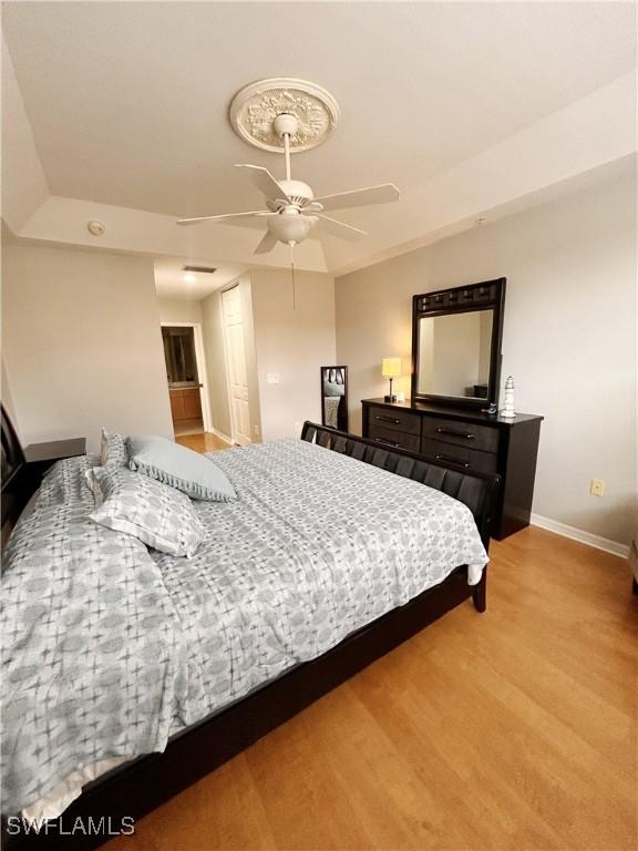 bedroom featuring a closet, baseboards, ceiling fan, and light wood finished floors