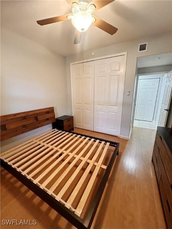 unfurnished bedroom with a closet, visible vents, ceiling fan, and light wood-style flooring