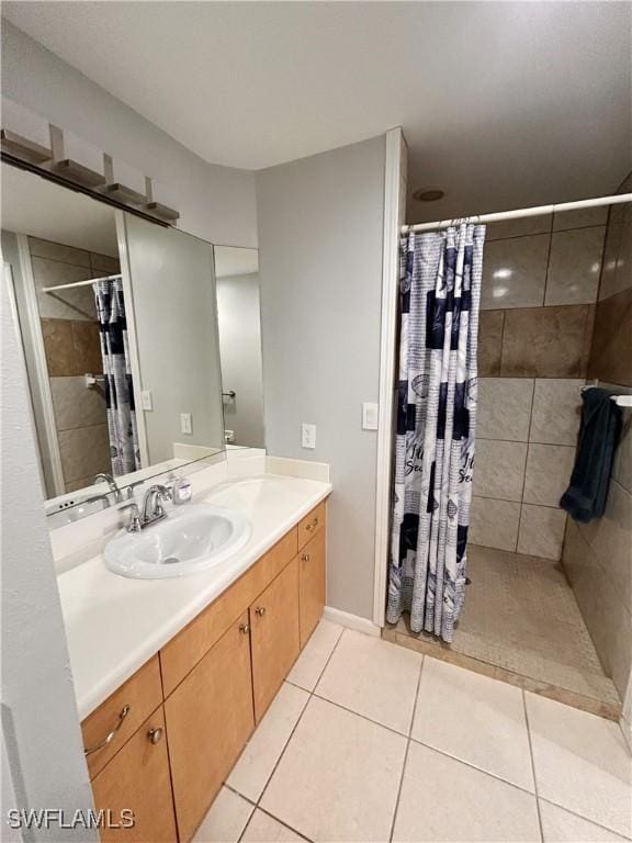 full bath with tile patterned flooring, a tile shower, and vanity