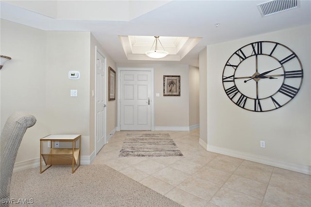 tiled foyer with ornamental molding, a tray ceiling, and a skylight