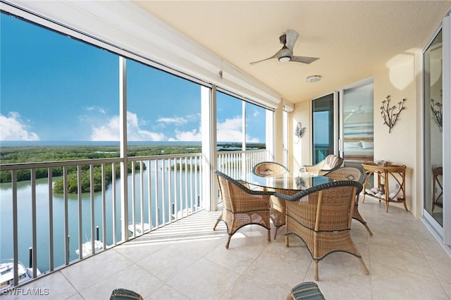 sunroom / solarium featuring a water view and ceiling fan