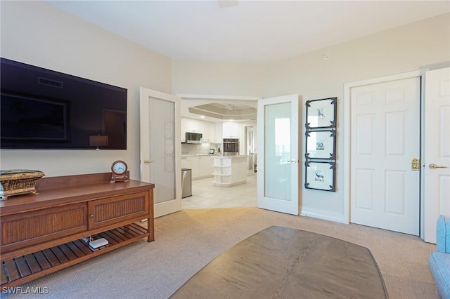 bedroom featuring connected bathroom, light carpet, and french doors