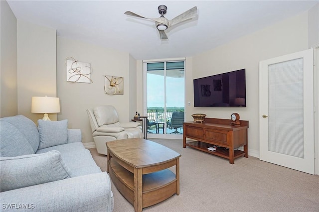 living room featuring light carpet, a wall of windows, and ceiling fan