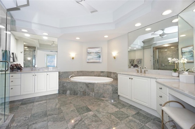 bathroom with a tray ceiling, shower with separate bathtub, and vanity