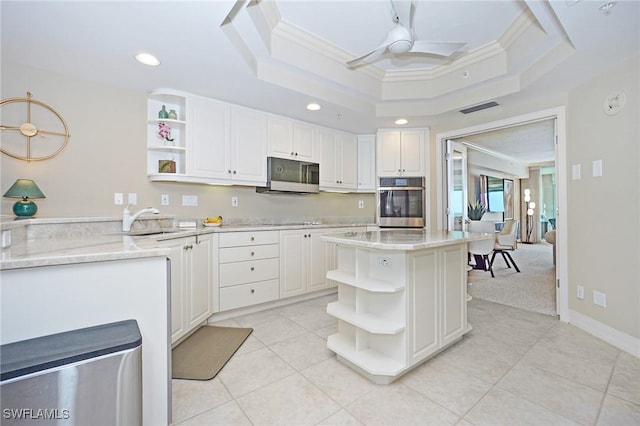 kitchen featuring a raised ceiling, crown molding, white cabinets, and oven